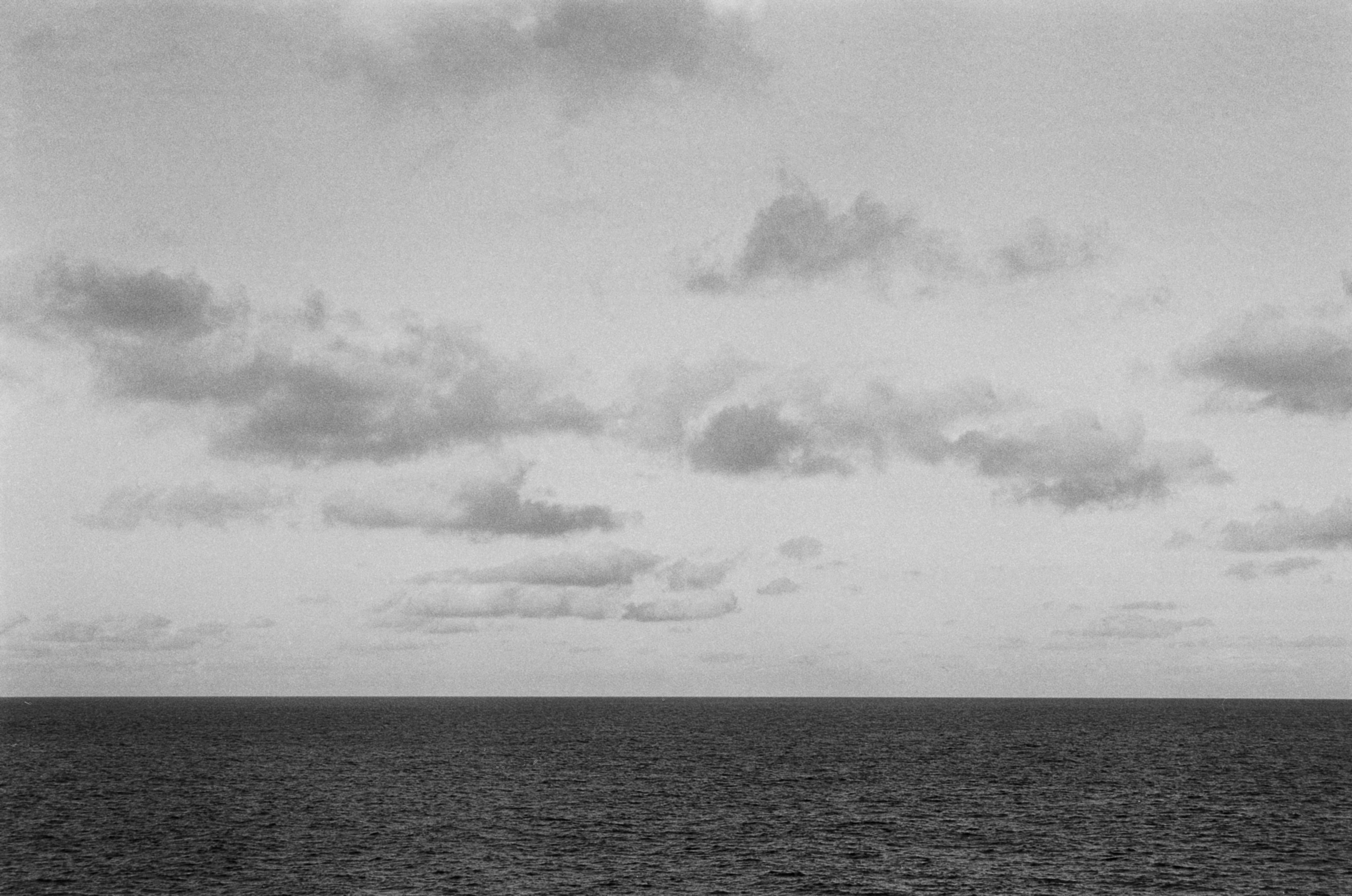 A monochrome ocean horizon beneath clouds.